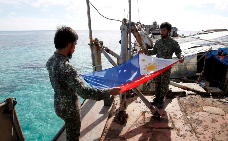2014年3月29日，菲律宾海军陆战队从“马德雷山”号军舰撤退期间折叠菲律宾国旗。（图取自路透社档案照）