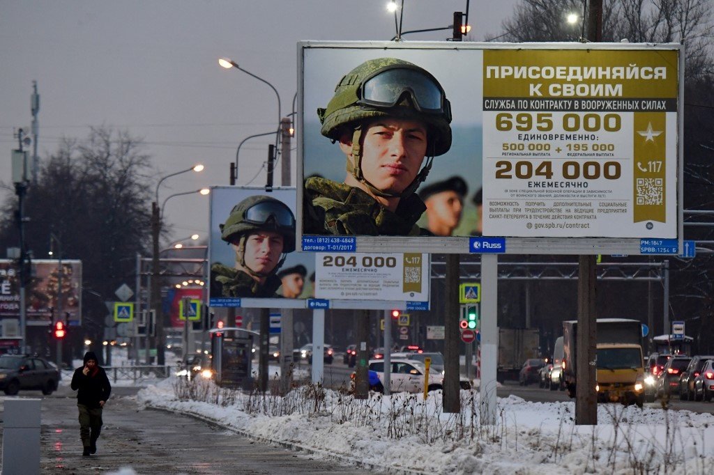 在俄罗斯第2大城圣彼得堡，一名男子周一走过宣传合约兵役的广告牌，上面写著“加入你的军队”。（图取自法新社）