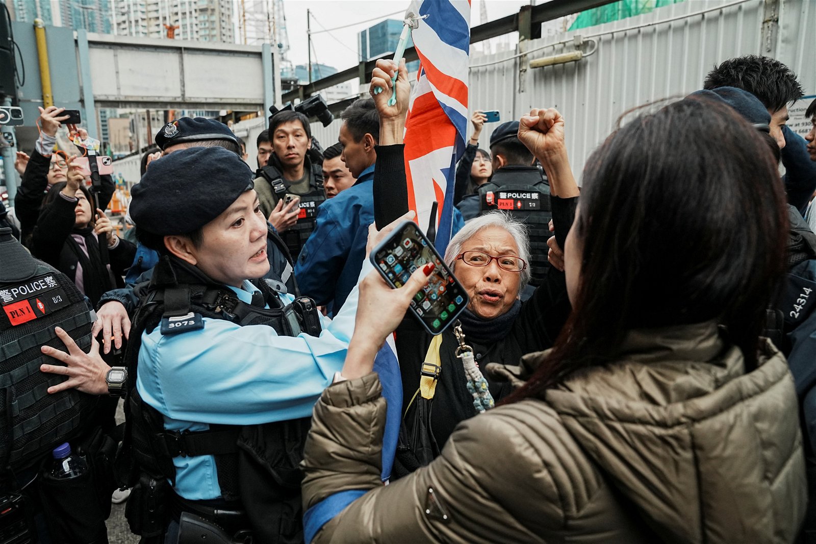 香港民运人士王凤瑶举起米字旗，周一上午在西九龙裁判法院外高喊口号。（图取自路透社）