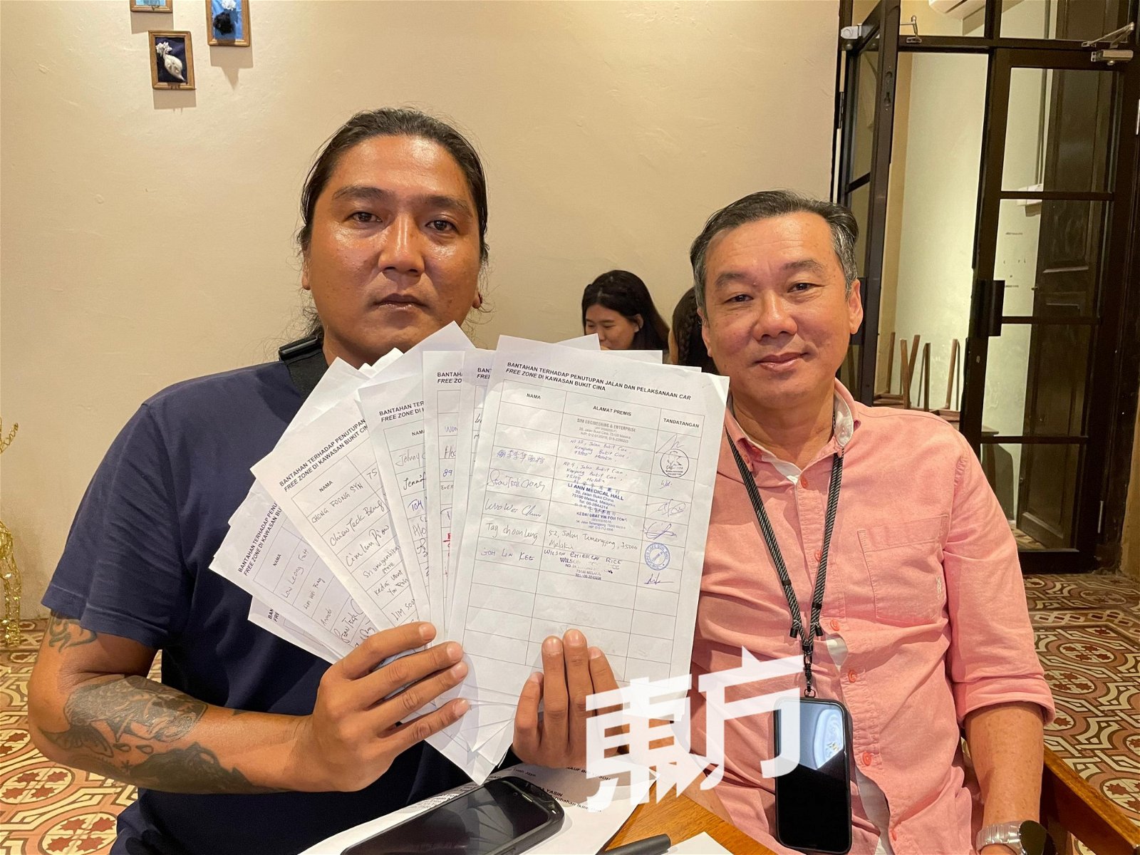 刘良发（左）展示三宝井居民及商家积极响应签署运动，右为郑添隆。