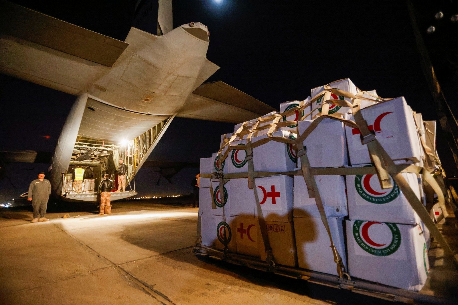 在伊拉克巴格达国际机场附近的一个军事空军基地，工作人员和安全部队正在处理来自红新月会的援助物资，这些物资将被运送到叙利亚的紧急救援飞机上，以援助致命地震的受害者。（图取自路透社）