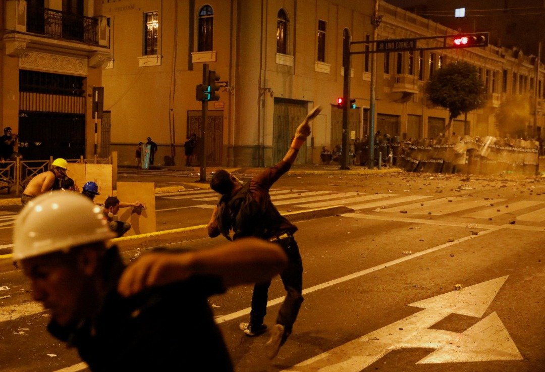 秘鲁示威终成暴力对抗，民众对武装警察投掷石块。（路透社）