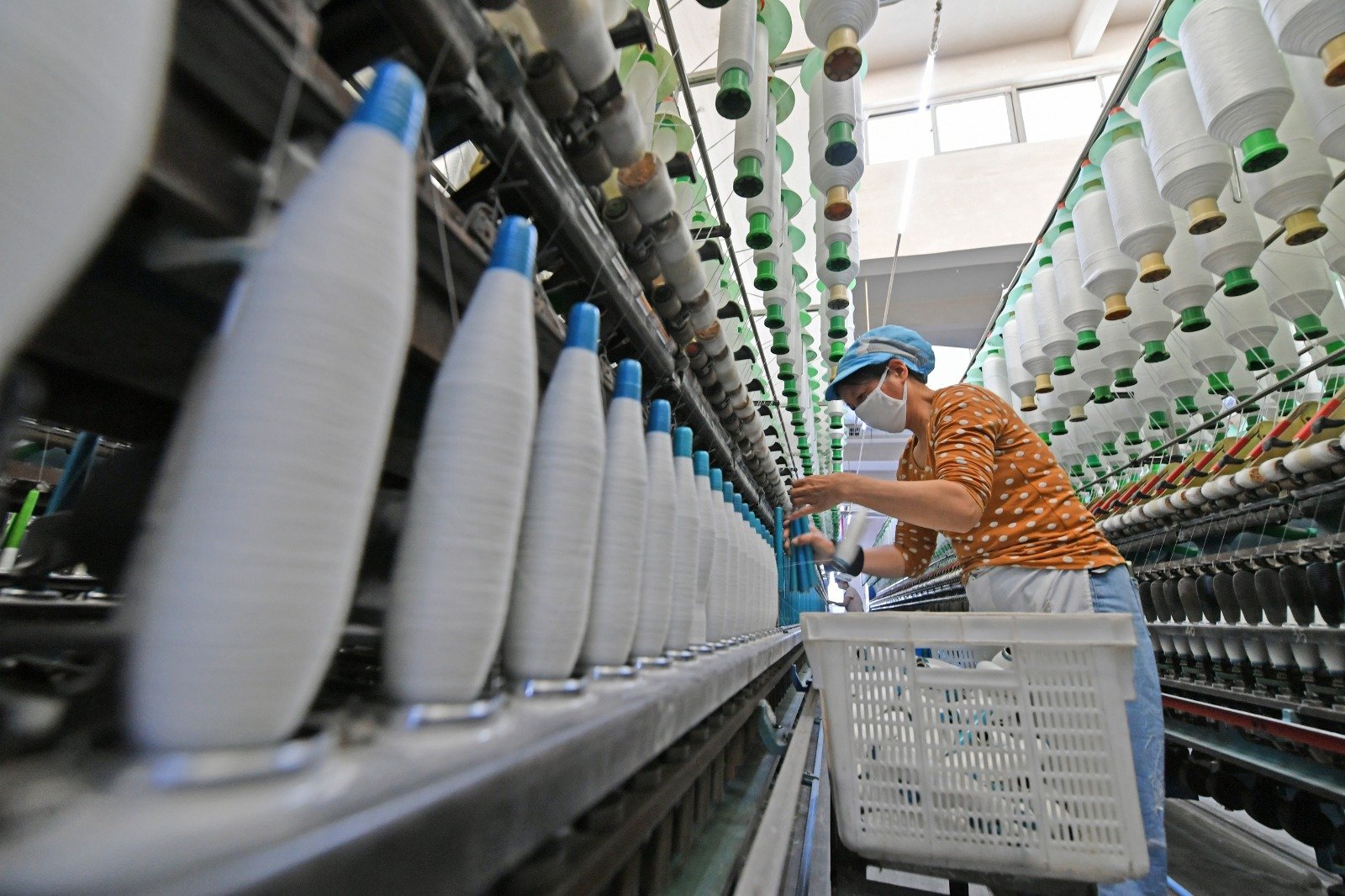 1月28日是春节假期结束后的返工首日，中国福建省泉州市一纺织工厂内的工人在纺纱生产线上忙碌著。（图取自中新社）