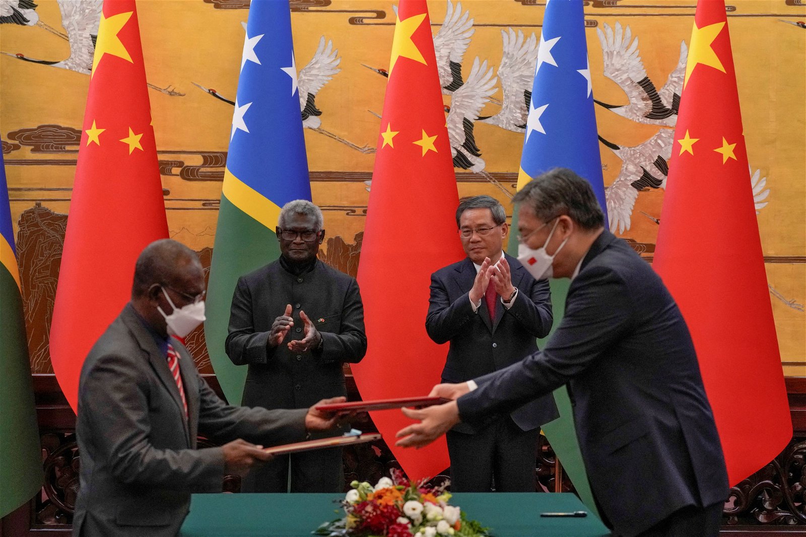 所罗门群岛总理索加瓦雷（后左）与中国总理李强（后右）周一签署协议，两国官员交换文件。（图取自路透社）