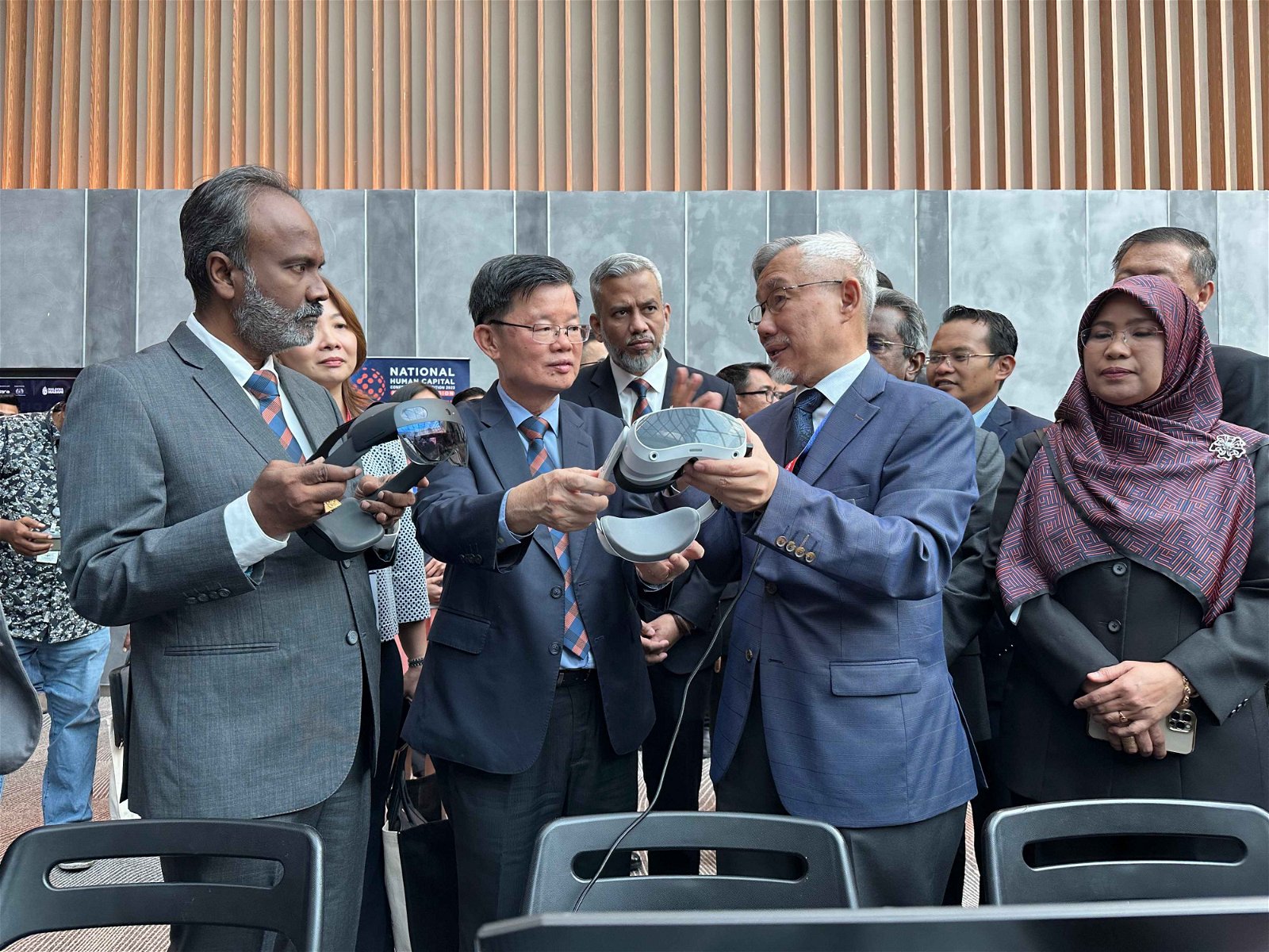 西华古玛（左起）及槟州首长曹观友聆听槟城技术发展中心首席执行员陈荣堂讲解现场展出的VR眼镜。