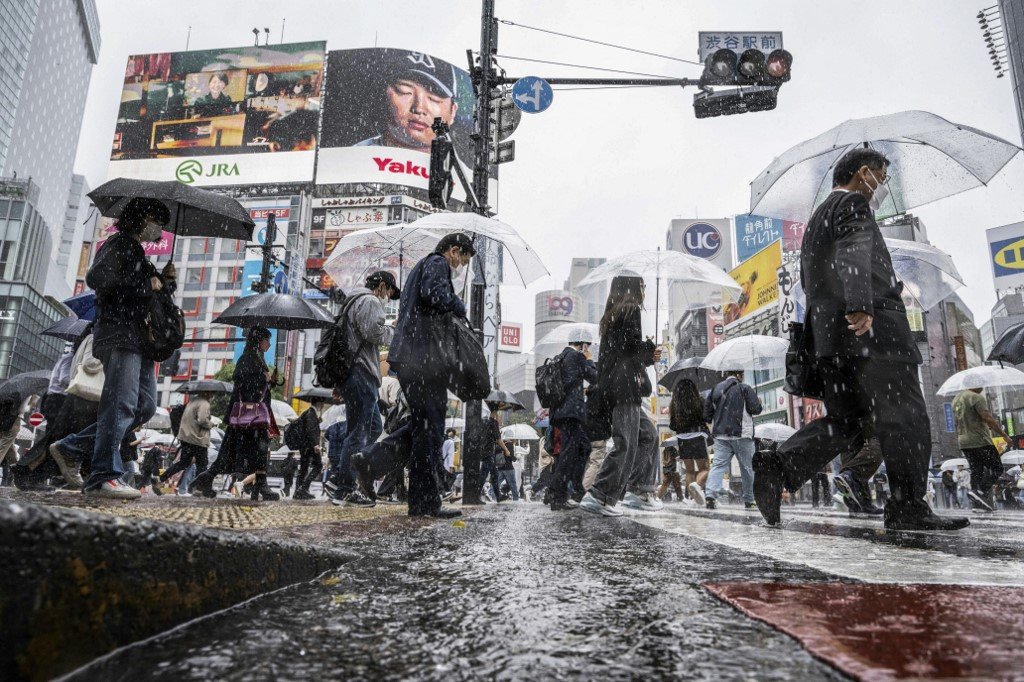 台风“玛娃”临近日本之际，周五在日本东京涩谷区，人们打伞避雨。（图取自法新社）