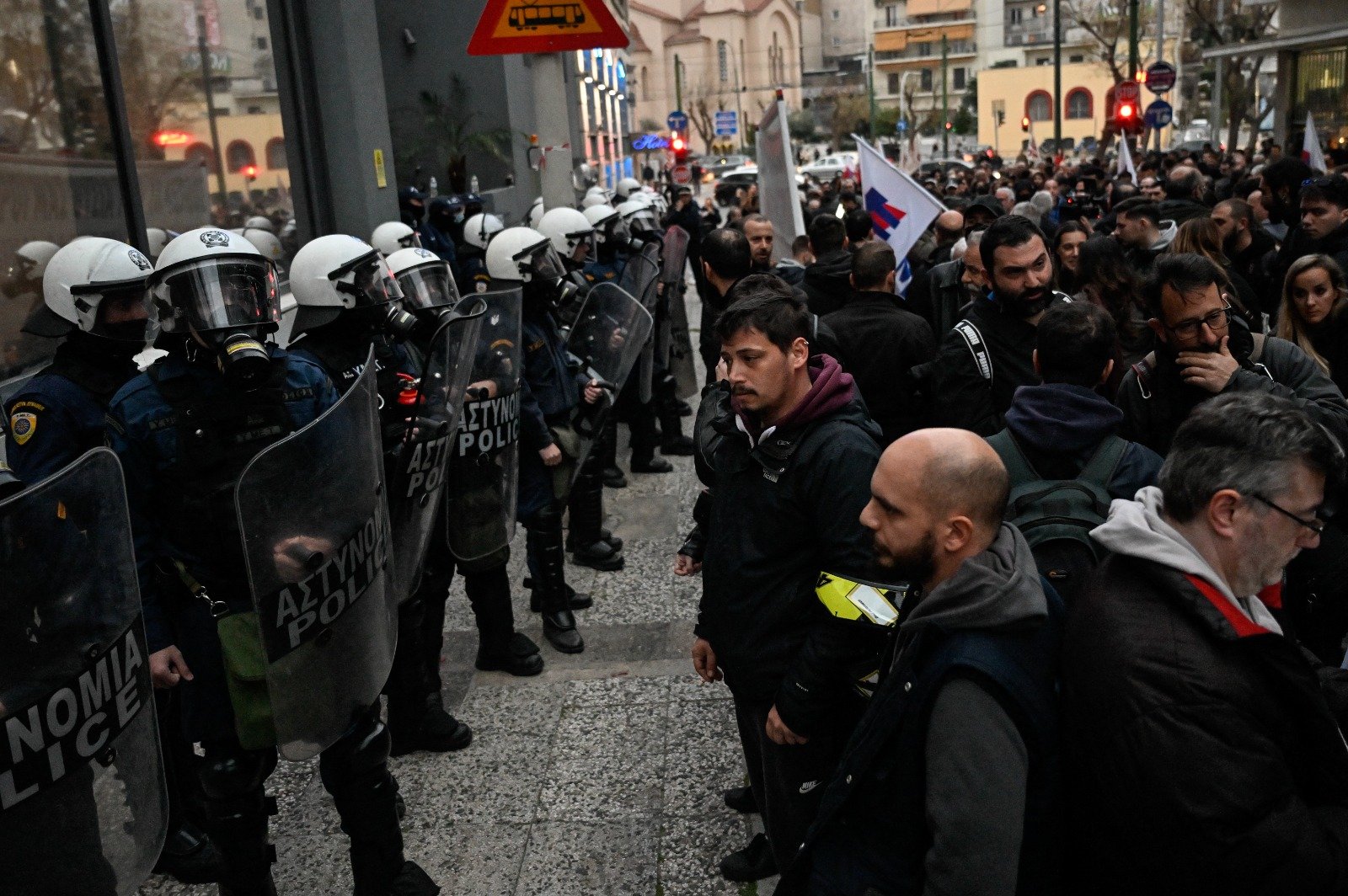 火车相撞事故引发民愤，民众在雅典希腊火车总部前示威，防暴警察在抗议期间组成安全警戒阵线。（图取自法新社）