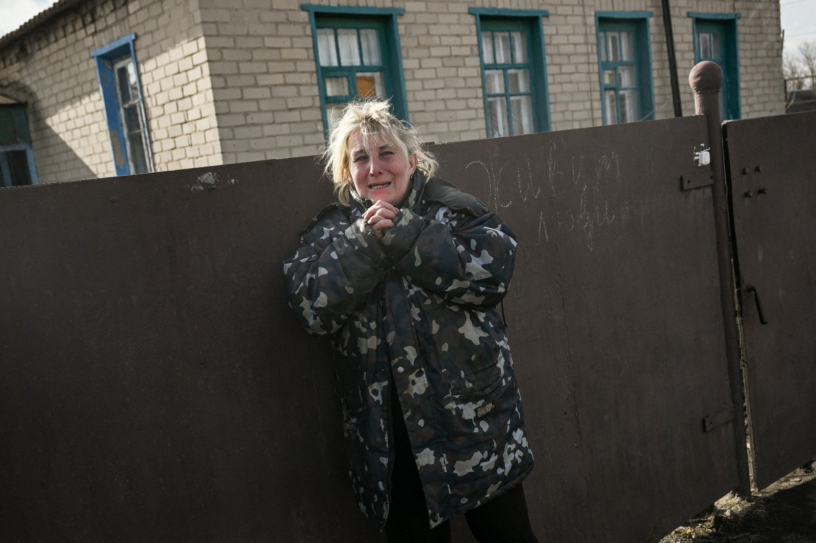 在巴赫穆特市附近城镇察苏夫雅，一名妇女听到炮击声惊恐地逃难到家门外。（图取自法新社）