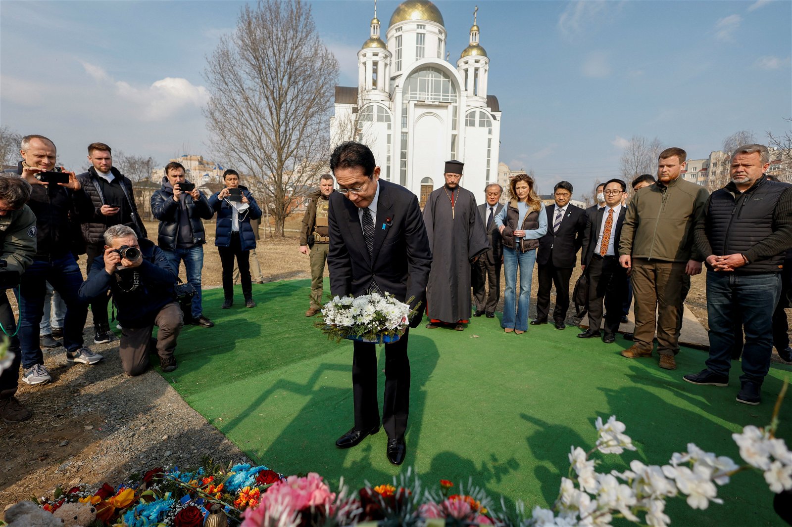 岸田周二在布查镇的一座教堂外献上花圈，悼念在战争中遇害的罹难者。（图取自路透社）