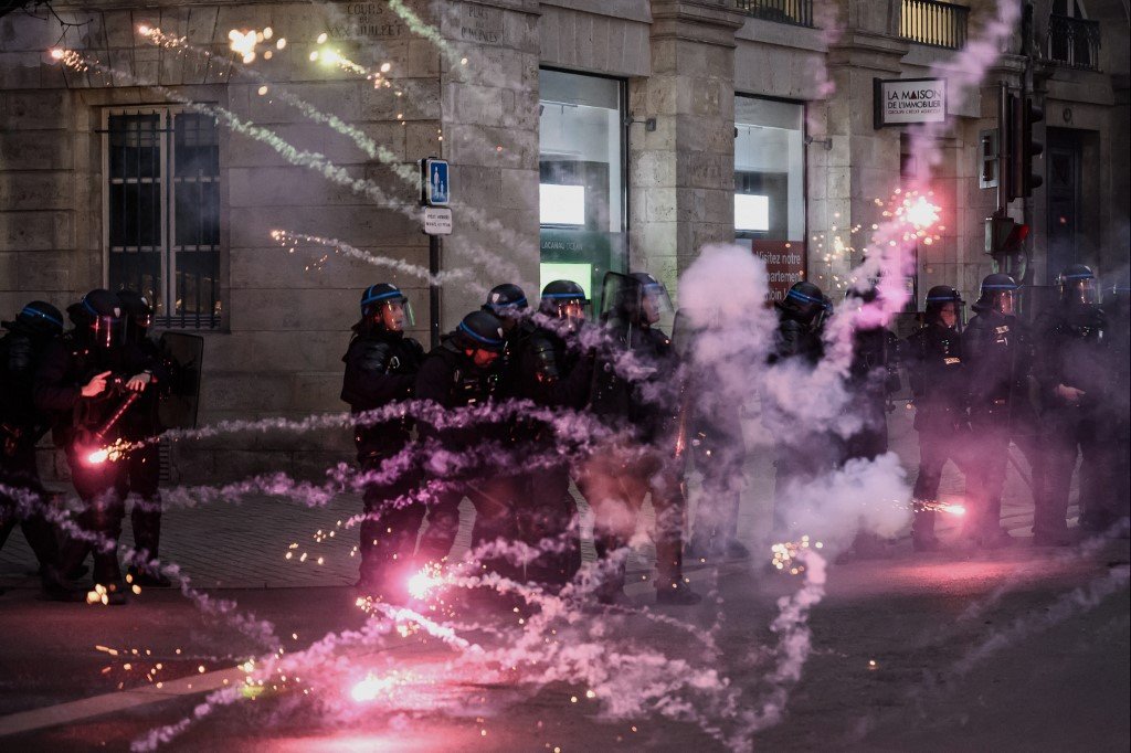 在法国西南部波尔多，不满政府强推退休改革制度的示威者在周三向防暴警察丢掷烟花。（图取自法新社）