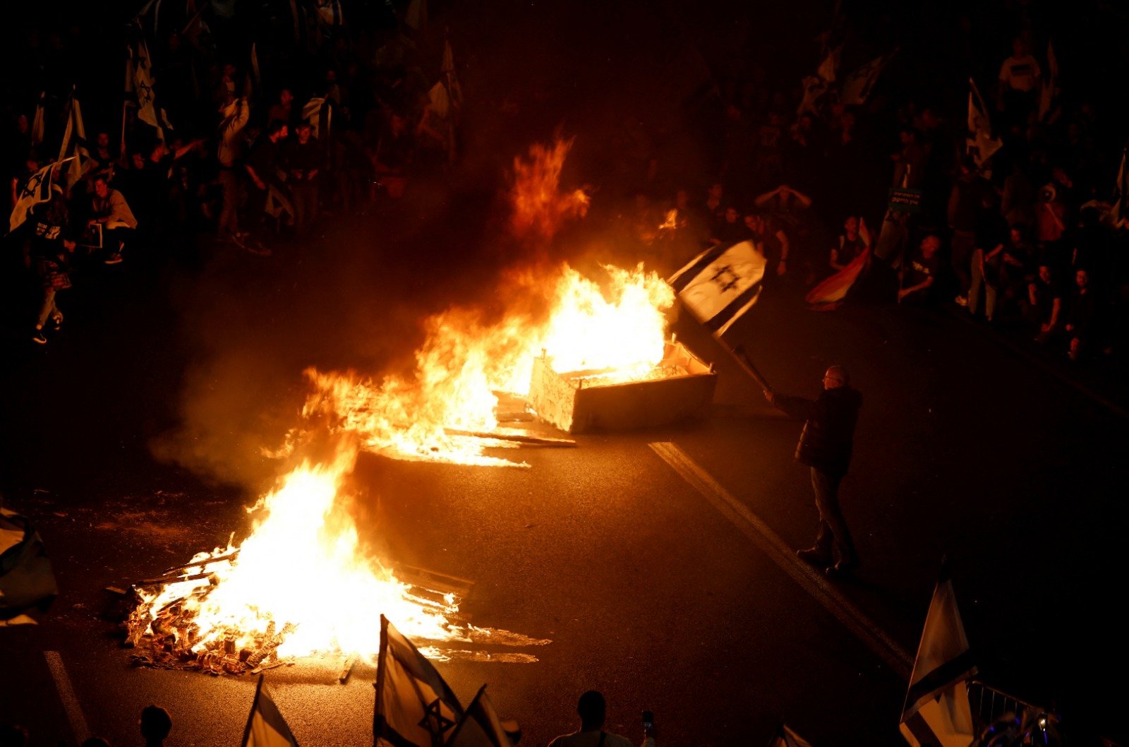 大批示威者堵塞特拉维夫的主要公路，又在公路上焚烧杂物。（图取自路透社）