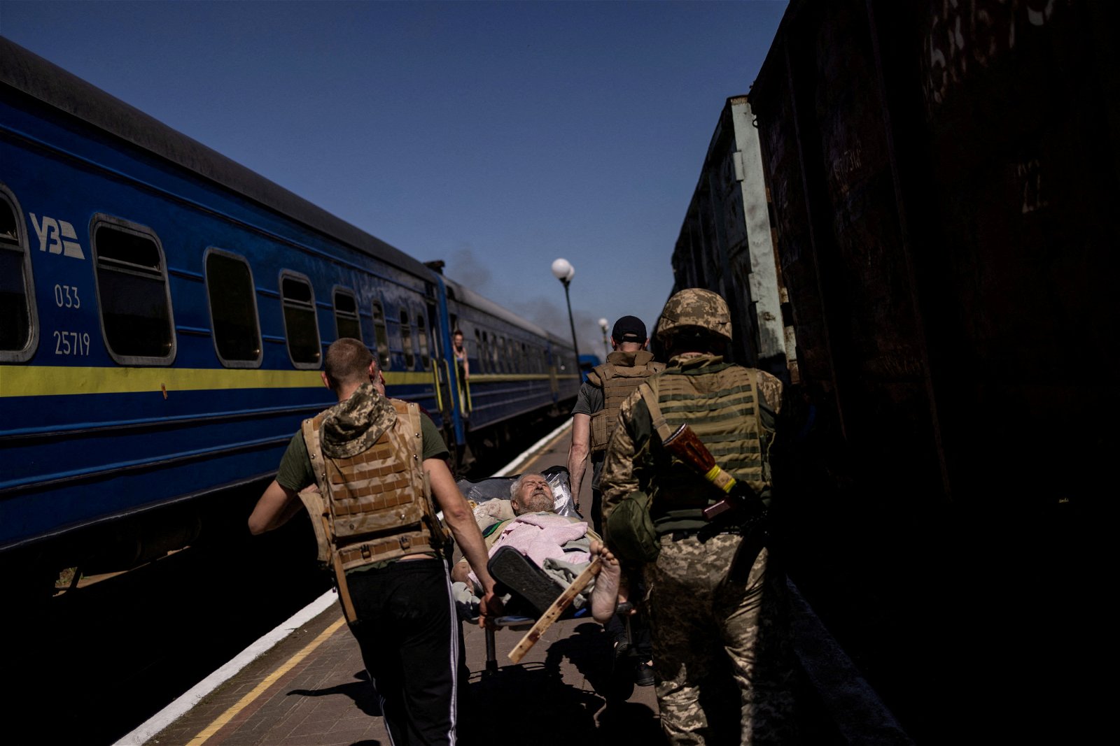 赫尔松火车站遭炮击，一列火车被击中，事后乌克兰军人到场营救伤者。（图取自路透社）