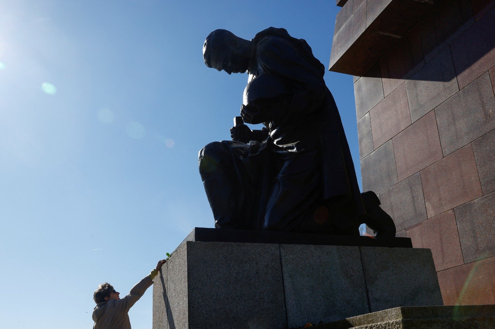 在德国柏林当地时间周一纪念胜利日和欧洲第二次世界大战结束78周年之际，一名游客向苏联战争纪念馆里的一名俄罗斯士兵雕像献花。（图取自路透社）