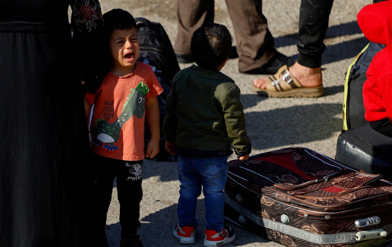 拥有双重国籍的巴勒斯坦人周一聚集在与埃及接壤的拉法边境口岸外，希望获得离开加沙的许可。图为一名等待中的小孩哭了起来。（图取自路透社）