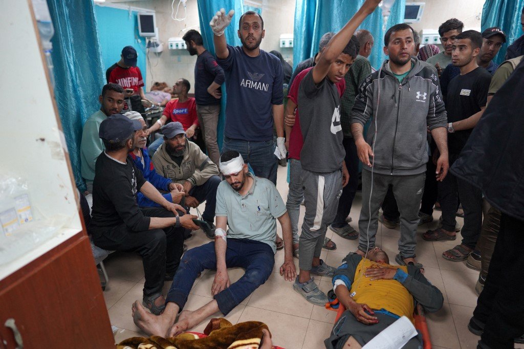 受伤的巴勒斯坦男子躺在阿克萨医院的地上等待治疗。（图取自法新社）