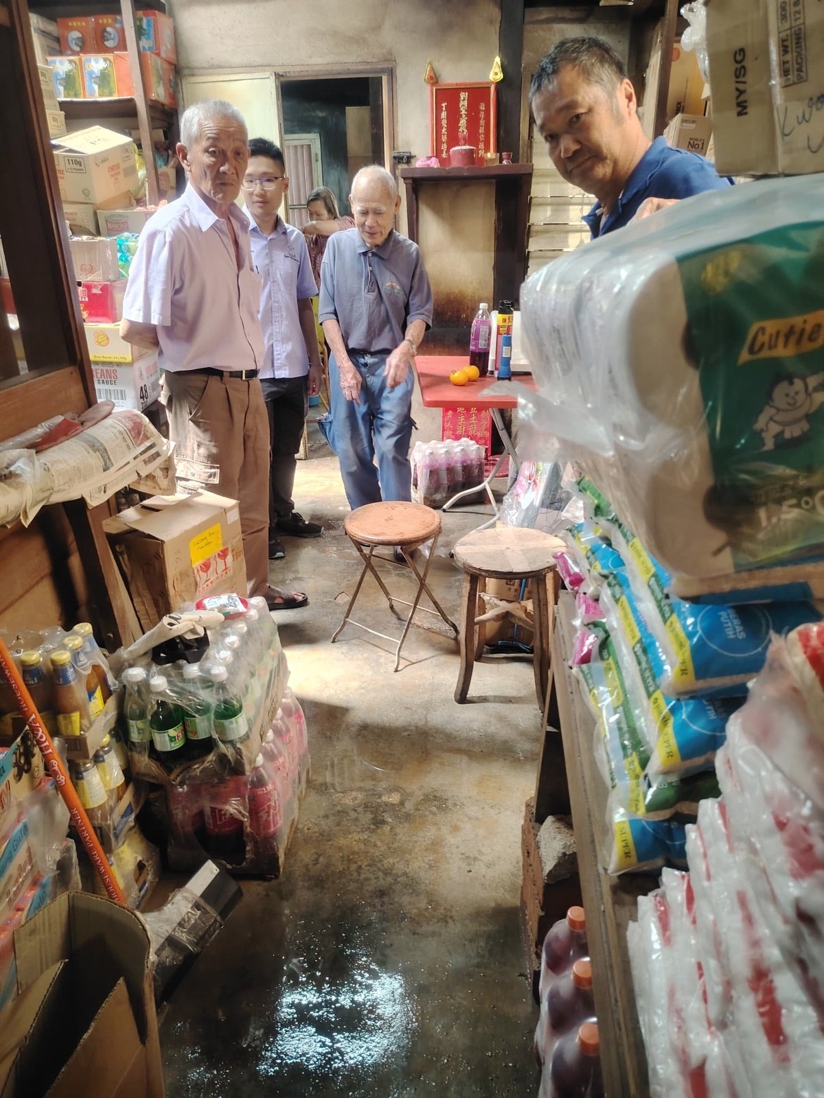 何子扬（左2）与行动党服务团队巡视其中一间面对闪电水患的杂货店。