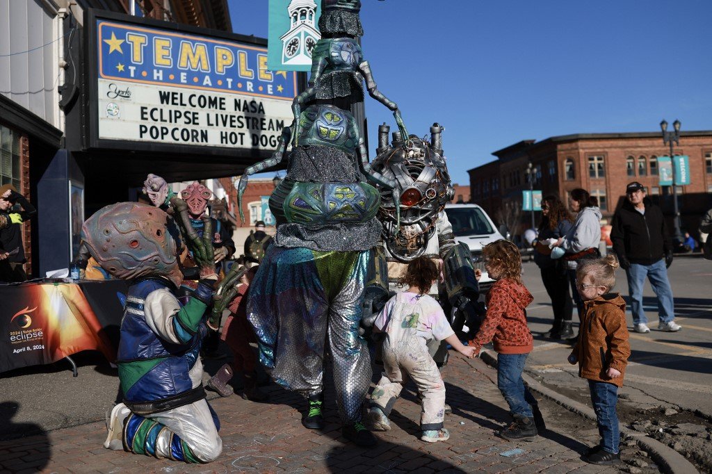 在缅因州霍尔顿的“日食节”期间，人们打扮成外星生物穿过广场，孩童高兴地围观。（图取自法新社）
