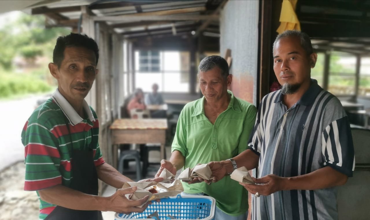 卡查里（左）与常客展示10年来保持每包售价50仙的椰浆饭。