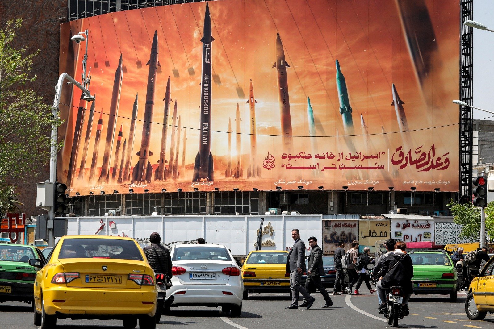 在德黑兰市中心的瓦莱亚斯广场，车辆驶过一块广告牌，广告牌上描绘了伊朗的弹道导弹，广告牌上用阿拉伯语写著“诚实的承诺”，用波斯语写著“以色列比蜘蛛网还要脆弱”。（图取自法新社）