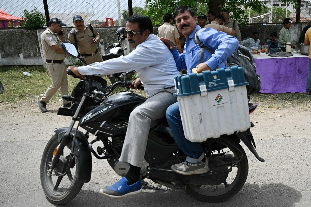一名选举官员从哈里瓦的投票材料分发中心领取电子投票机 (EVM) 后骑上摩哆离开。（图取自法新社）