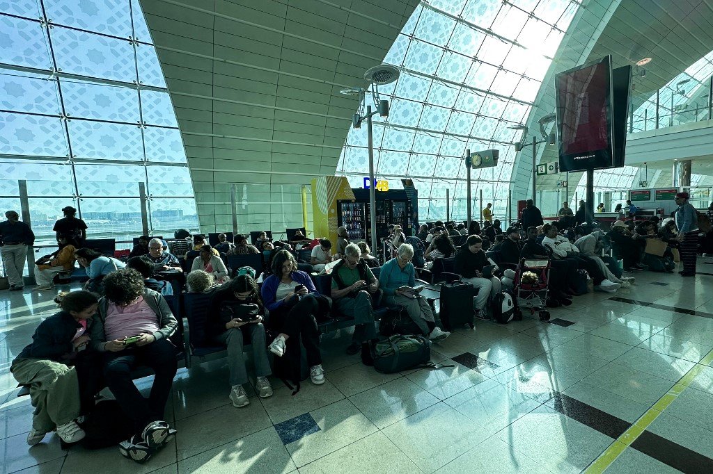 因洪水几近瘫痪的迪拜国际机场，周四分流了数十架入境航班。图为乘客在机场等待航班。（图取自法新社）