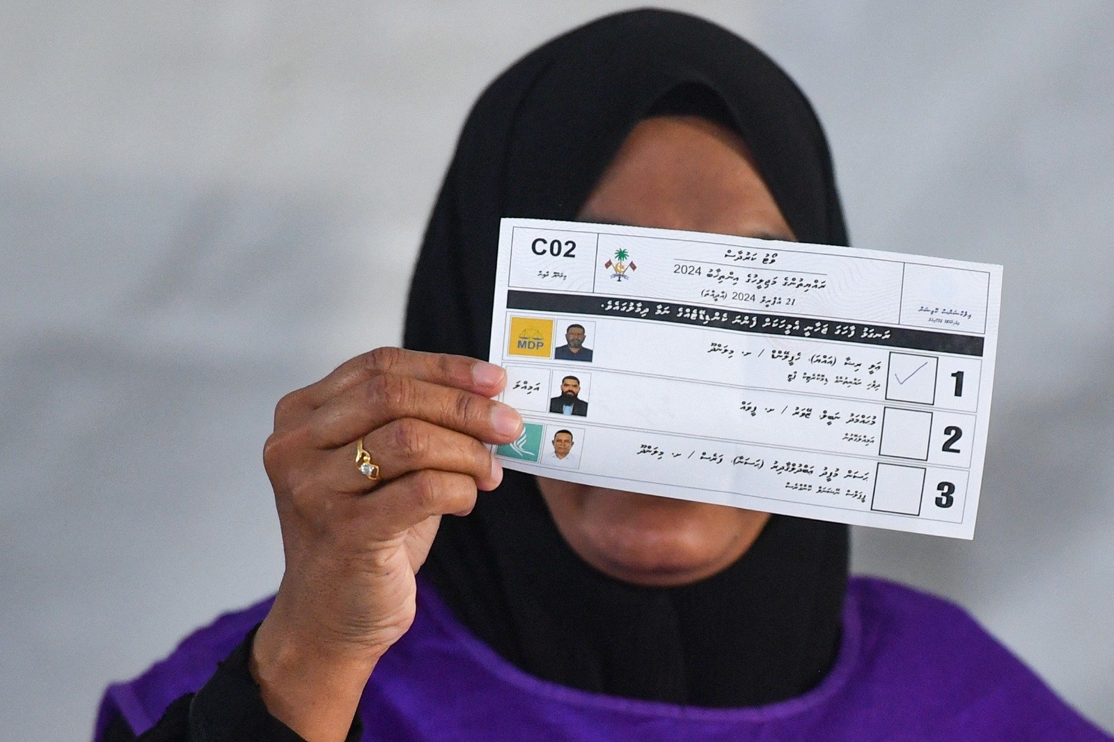 一名官员在周日投票结束后计票时展示选票。（图取自法新社）