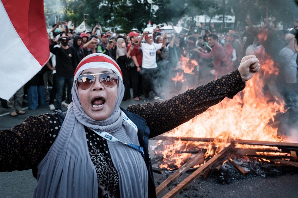 印尼宪法法院周一驳回了推翻普拉博沃赢得总统选举的上诉申请，示威者闻讯后情绪激动，烧毁总统佐科肖像的海报泄愤。（图取自法新社）