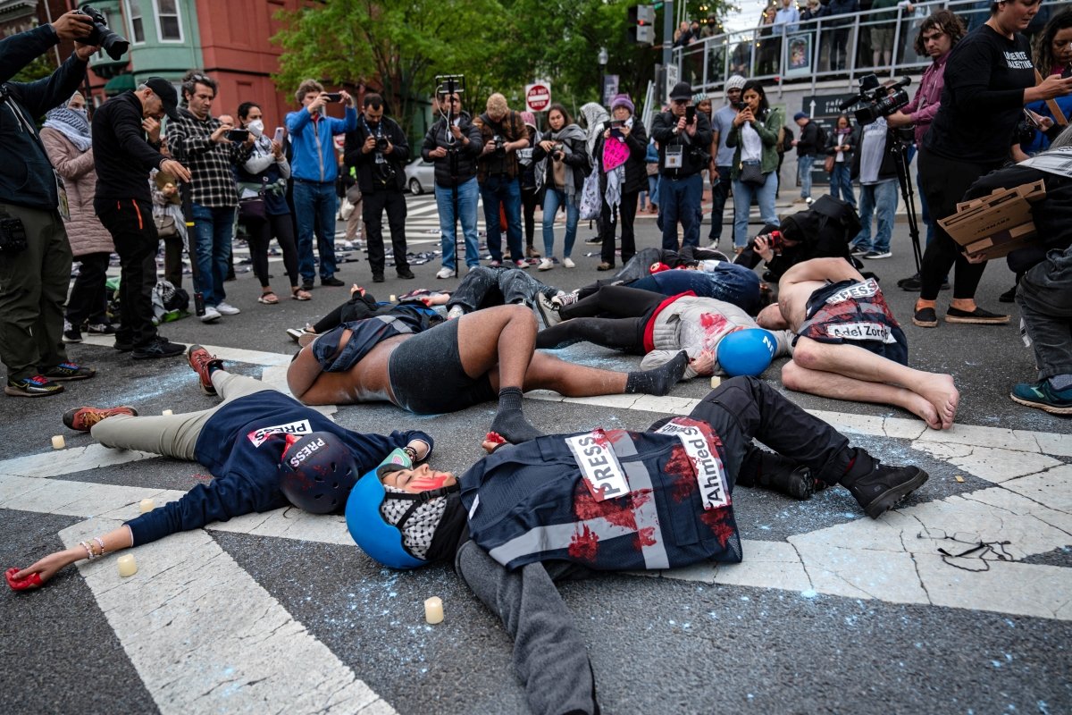 在白宫记者协会晚宴举办地希尔顿酒店的入口处，一群示威者躺在大马路上，象征在以巴战争中遇害的新闻从业员。（图取自法新社）