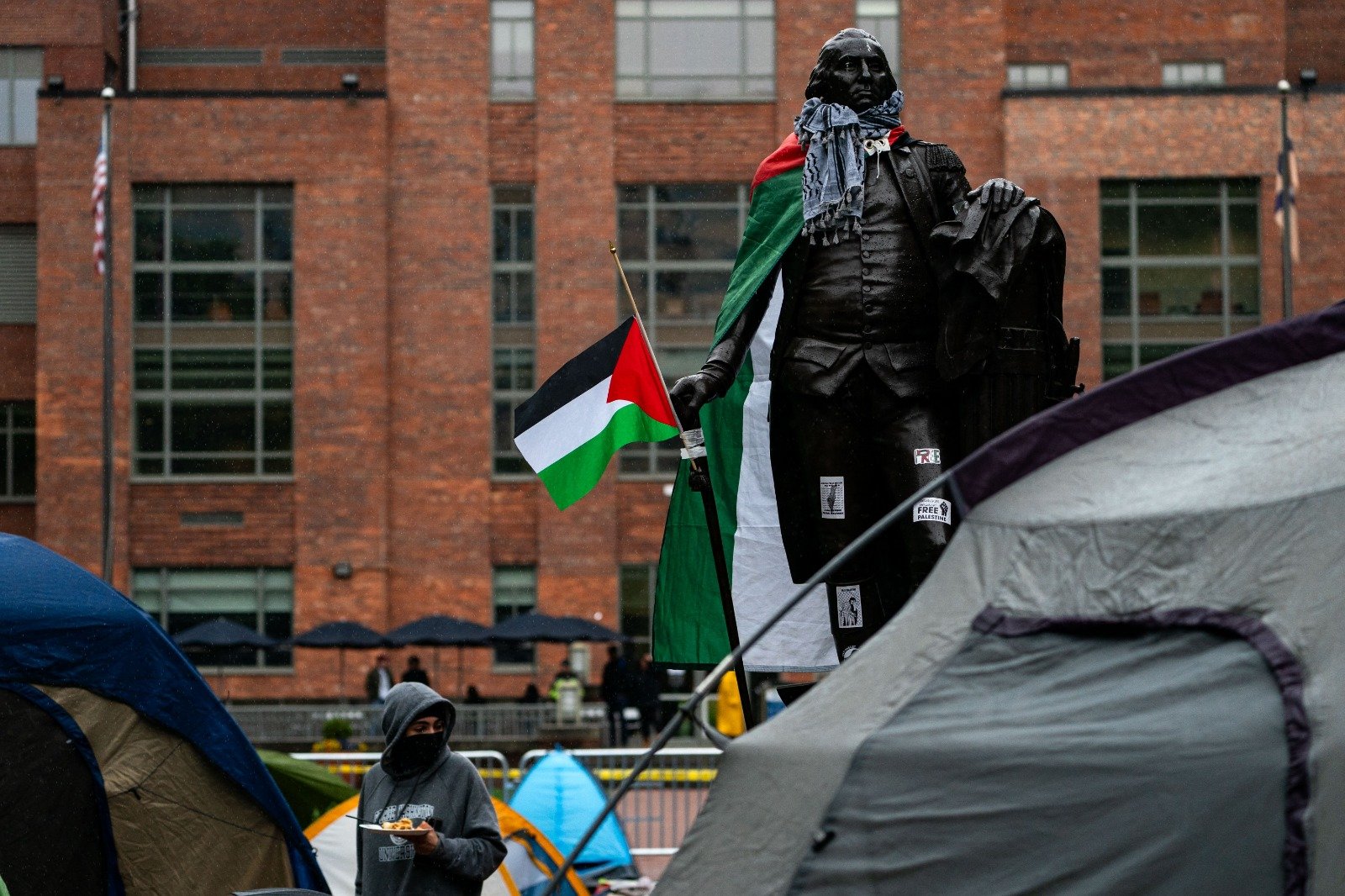在乔治华盛顿大学校园内的抗议营地，乔治华盛顿的雕像被视为学生披上巴勒斯坦旗，脖子上还有阿拉伯头巾。（图取自法新社）