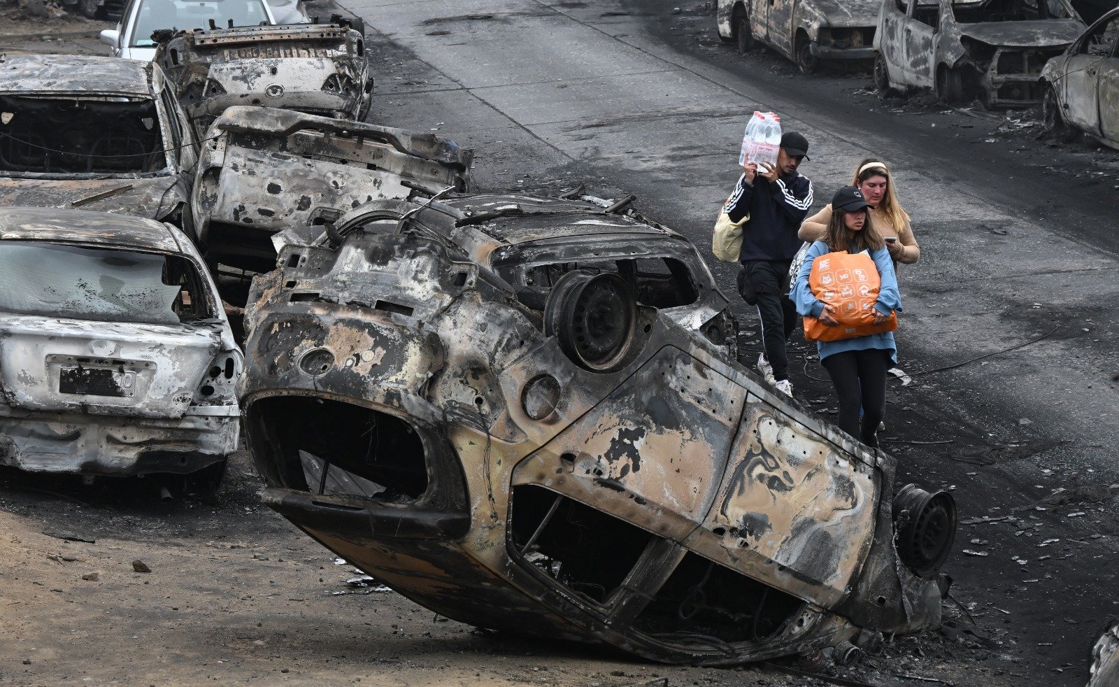 智利比尼亚德尔马基尔普埃发生森林火灾后，人们周日走过被烧毁的车辆。（图取自法新社）