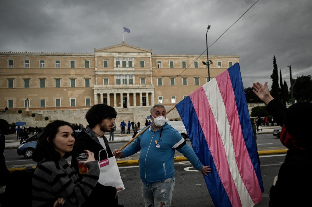 希腊议会外，一名男子当地时间周四与LGBTQ社群成员聚集时拿著跨性别旗帜。（图取自法新社）