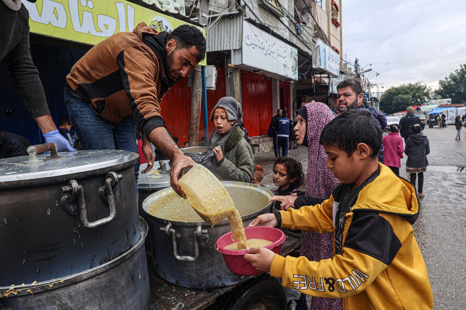 一名志工周日在加沙地带南部拉法，向流离失所的巴勒斯坦人分发口粮红扁豆汤。（图取自法新社）
