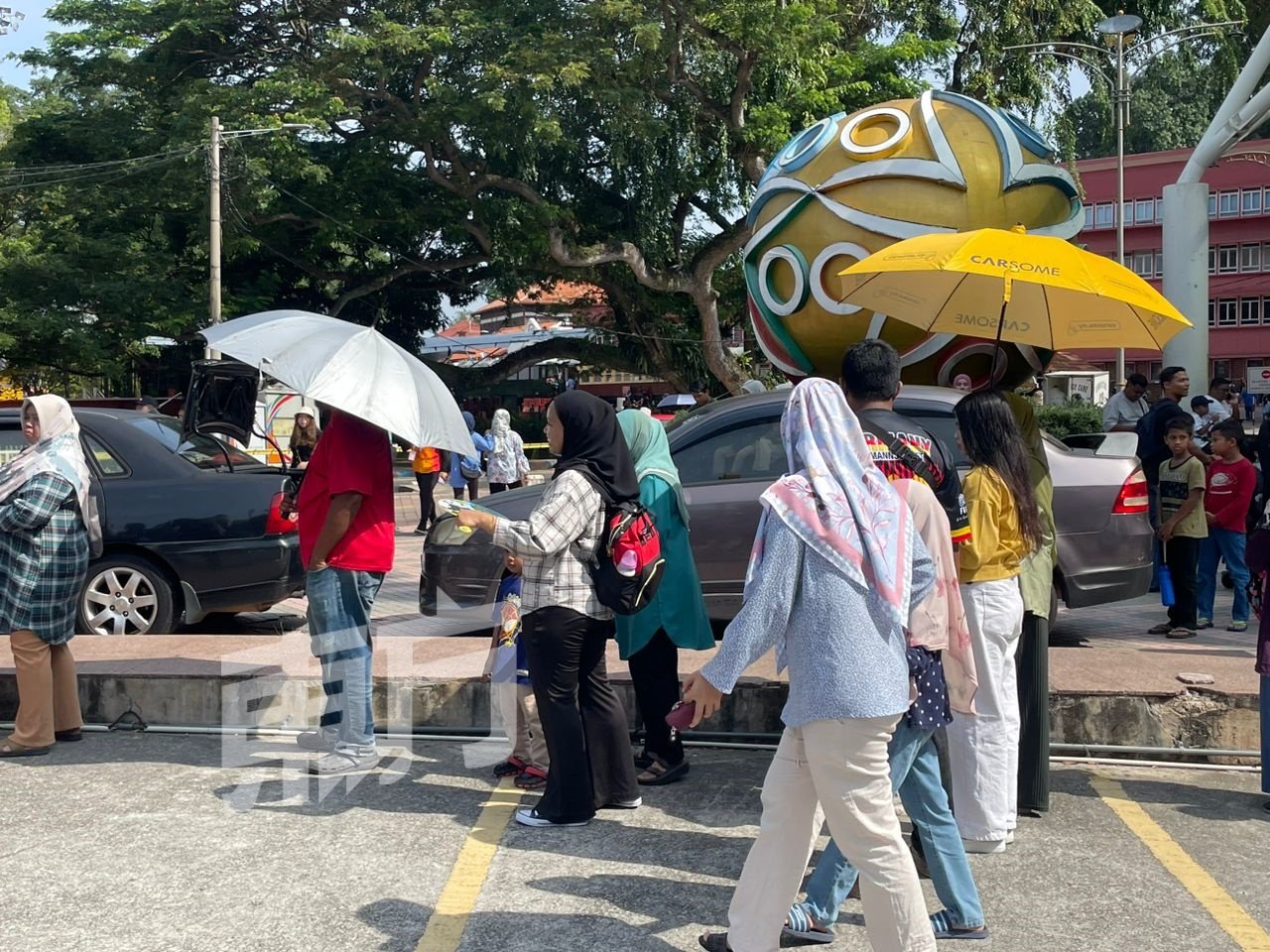 民众撑雨伞，在烈阳下排队等候。