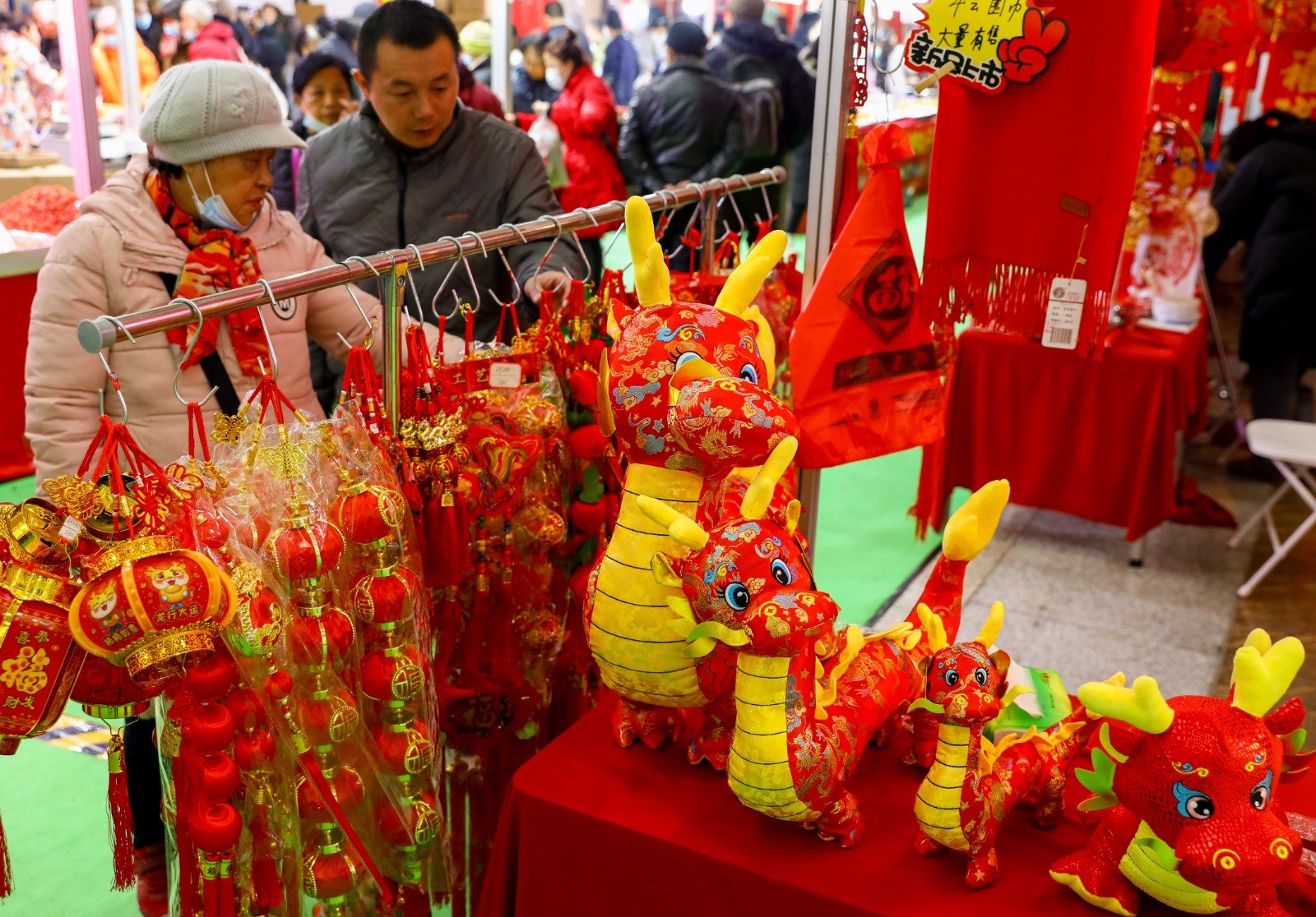 1月27日在中国湖北武汉举行的2024湖北(武汉)农产品新春购物节暨“江城百臻”年货节上，众多年货吸引民众前来选购。图为市民购买龙年装扮摆件。（图取自中新社）