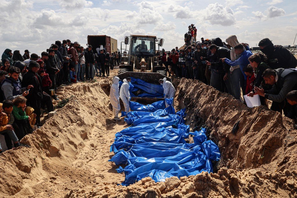 加沙地带南部拉法周四举行的大规模葬礼上，哀悼者看著医务人员准备埋葬47名巴勒斯坦人的遗体，这些尸体一度被以色列带走。（图取自法新社）