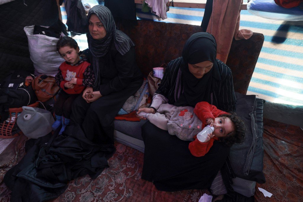流离失所的巴勒斯坦妇女，周四在加沙南部拉法的一个帐篷里照顾孩子。（图取自法新社）