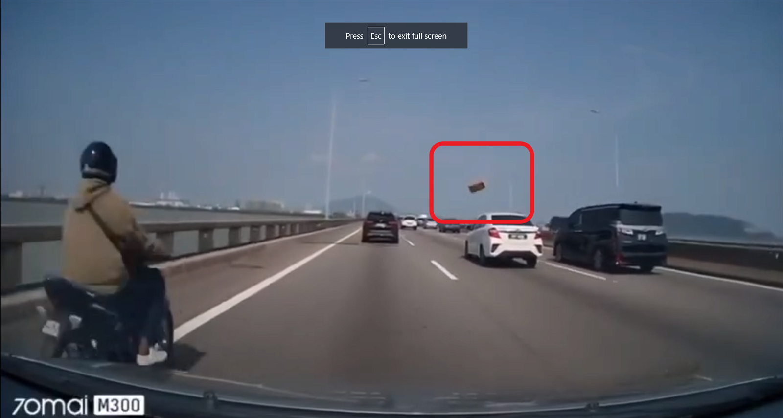 行车记录器画面显示，从隔壁车道，突然飞来一个纸箱。