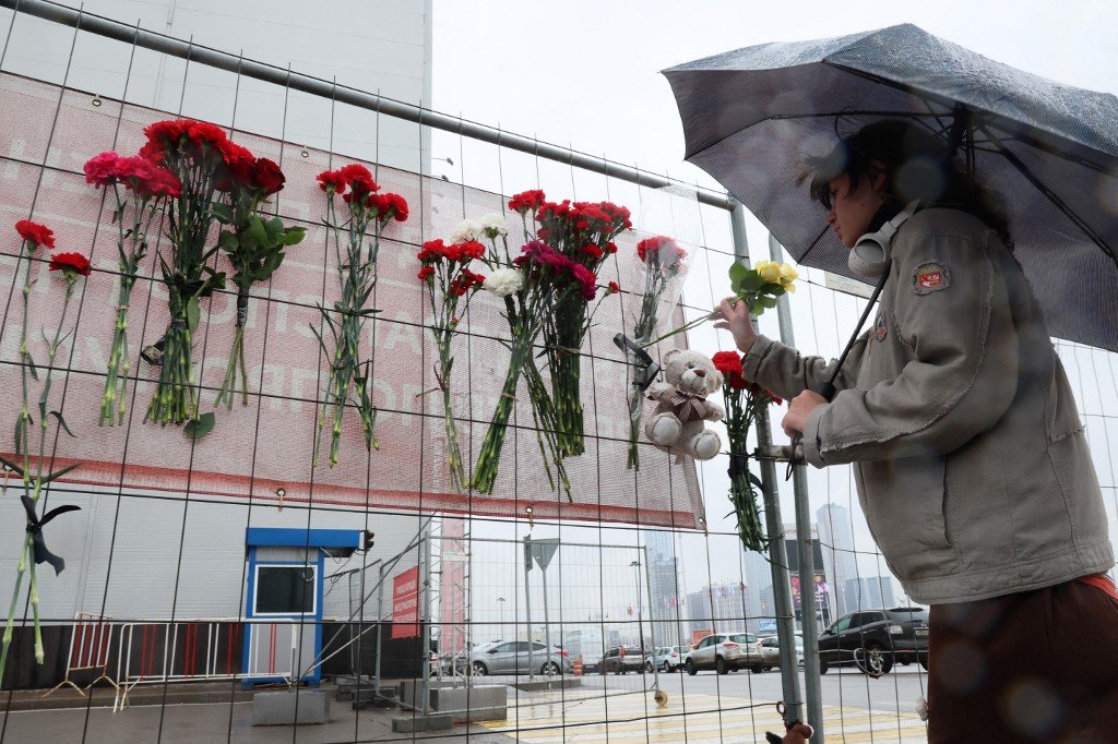 俄罗斯莫斯科近郊周五发生恐袭事件一天后，民众在番红花市政厅音乐厅会前的临时悼念处献花致意。（图取自法新社）