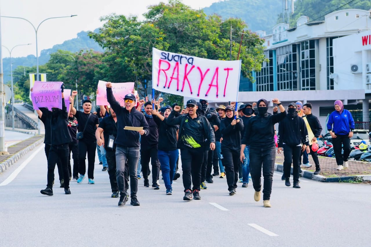 150名扮演滋事者的黑衣人高举写有“SUARA RAKYAT”及“KAMI SEDANG DIZALIMI”字样的大字报，步行前往州政府大厦抗议。（图：霹雳警方）