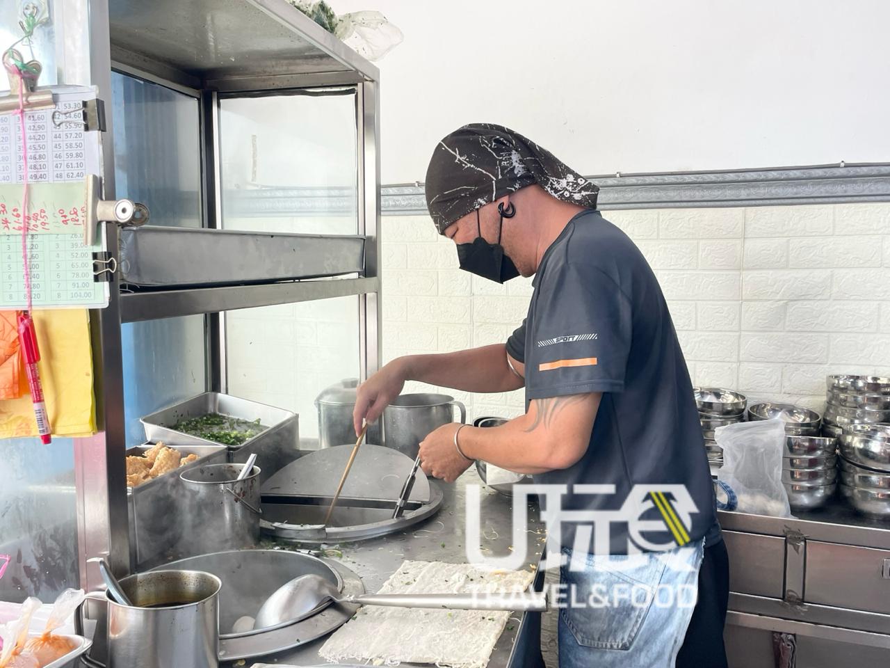 蓝仁俊以艺术潮流匠人造型，在店前忙著完成食客订单，认真地烹煮每一碗粉面和酿豆腐。