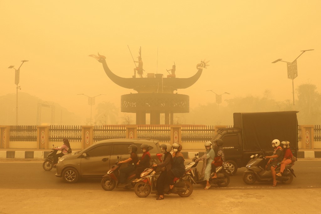 上周六在帕朗卡拉亚笼罩在浓重烟霾中，摩哆骑手戴著口罩出勤。（图取自法新社）