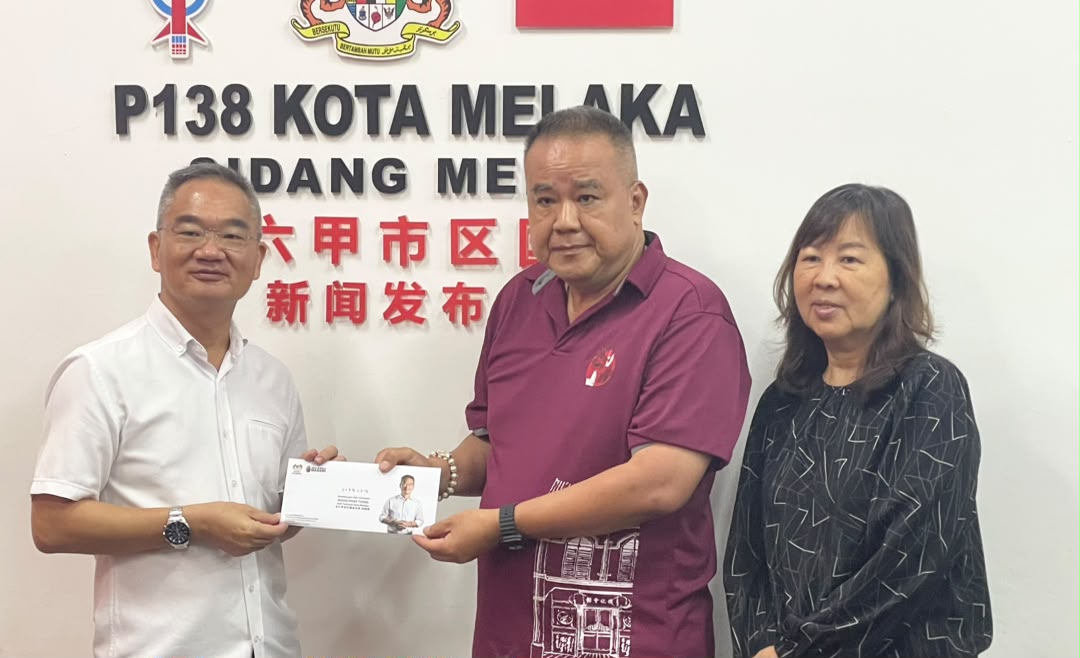 马六甲德化会馆总务陈金顺（右2起）从邱培栋手中接领拨款支票。