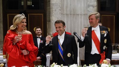 荷兰国王伉俪周二在王宫设国宴，款待国事访问的法国总统马克龙（中）。（图取自法新社）