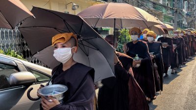在缅甸最大城市仰光，一群比丘尼4月24日在头顶上放著毛巾并打著雨伞，在热浪下化缘。（图取自法新社）
