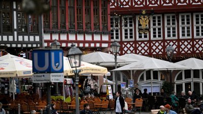 一名妇女上周五走过德国西部美因河畔法兰克福中央罗默广场的街头咖啡馆。（图取自法新社）