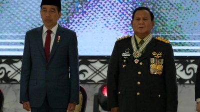 印尼总统佐科（左）与印尼防长、准总统普拉博沃2月28日在雅加达军事总统出席活动时唱国歌。在当天，佐科授予普拉博沃四星上将军衔，而此举遭人权组织批评是要洗白普拉博沃的政治污点。（图取自法新社）