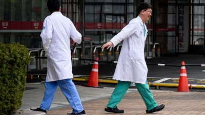 在韩国加图立大学首尔圣玛丽医院外，两名相遇的医护人员互相打招呼。（图取自法新社）