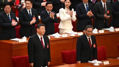 中国国家主席习近平（前左）及国务院总理李强周二早抵达北京人民大会堂，出席十四届全国人大二次会议开幕时，现场委员起身鼓掌。（图取自法新社）
