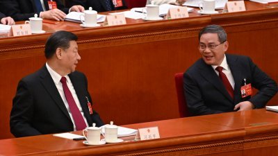 中国十四届全国人大二次会议周二早在北京人民大会堂开幕，国务院总理李强在完成《政府工作报告》，回到座位后与中国国家主席习近平（左）交谈。（图取自法新社）