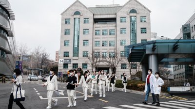 一群医务人员在周二步出韩国首尔一家医院。（图取自法新社）